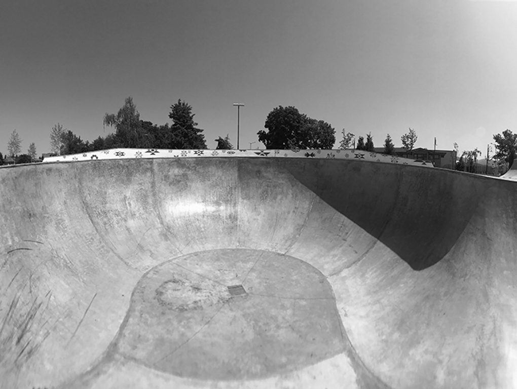 Deep concrete skatepark bowl with smooth transitions and a patterned coping edge