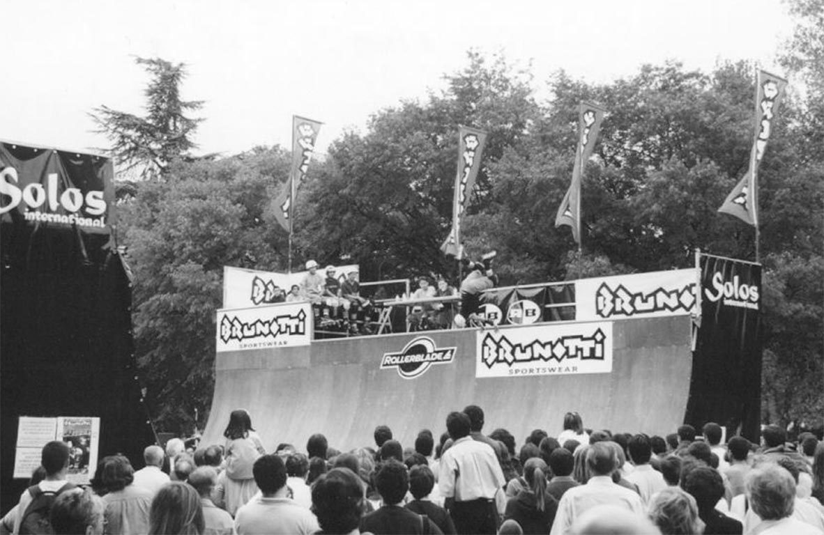 Large crowd watching a skater on a sponsored portable halfpipe at an outdoor contest
